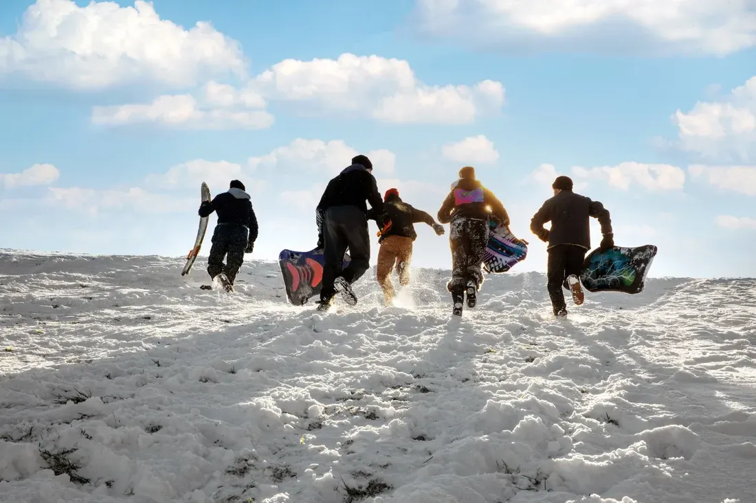 Students running up a hill to go sledding during the winter.